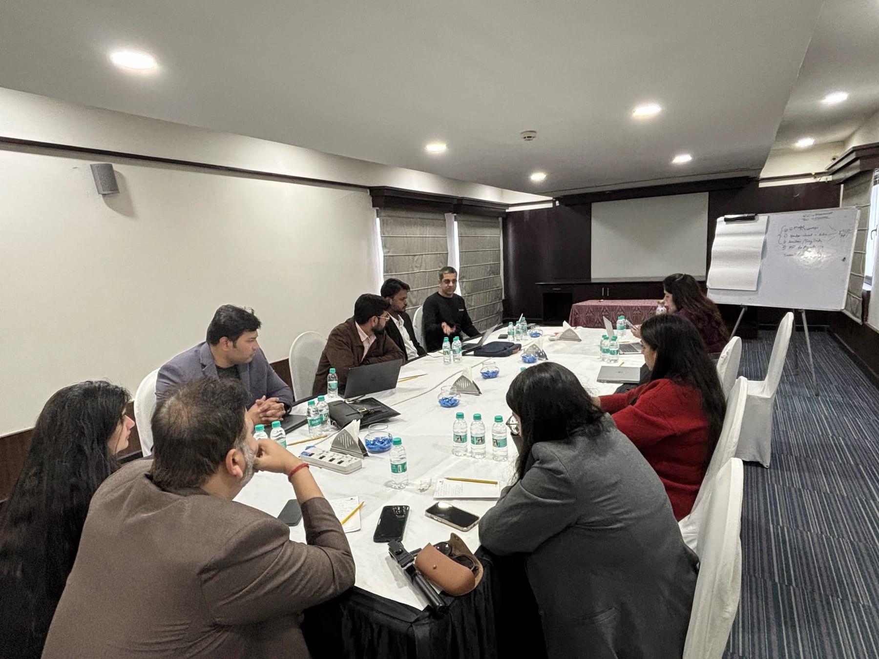 Infollion team members in a working session around a conference table, with laptops and a whiteboard of notes behind them.